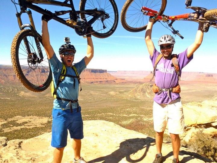 two people lifting their moutain bikes above their heads